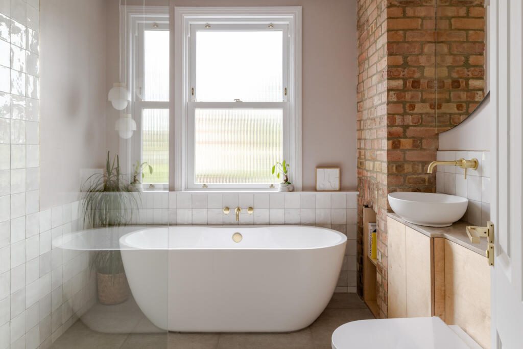 Bathroom with freestanding bath, exposed brick chimney breast and brass fittings, from an earlier project by Phil and Jen.