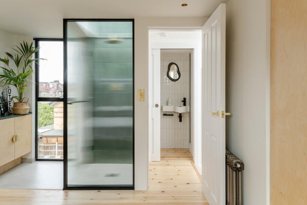 Landing with reeded glass screen, pine floorboards and a cast iron radiator, from an earlier project by Phil and Jen.