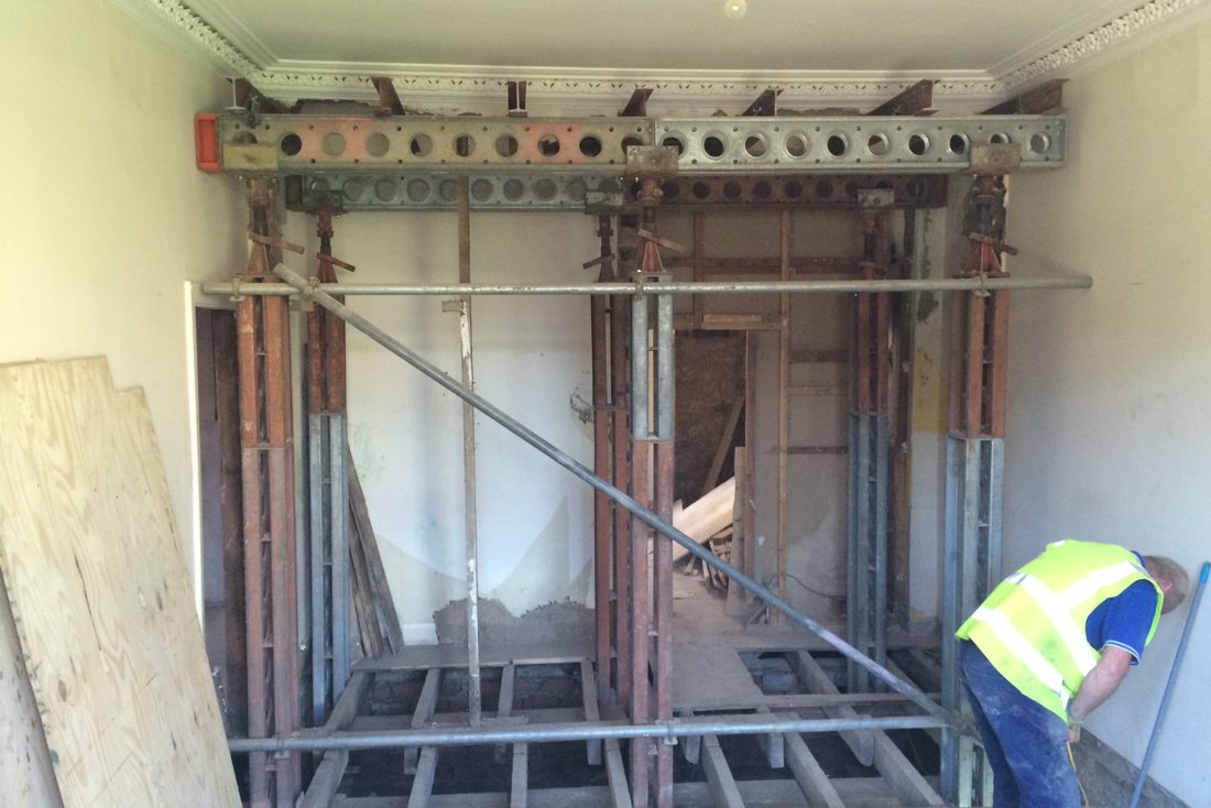 Temporary works propping a four-storey building on acro-props and strongboy beams during structural alterations.
